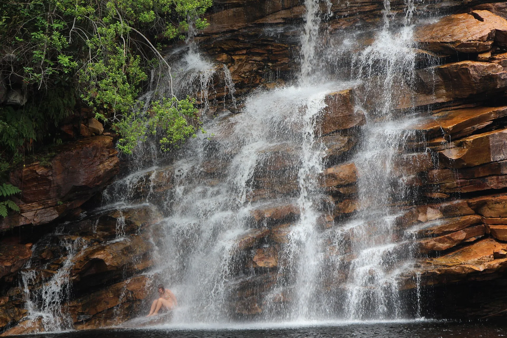 Cachoeira de grande volume escorrendo por paredão de rocha avermelhada na Chapada Diamantina
