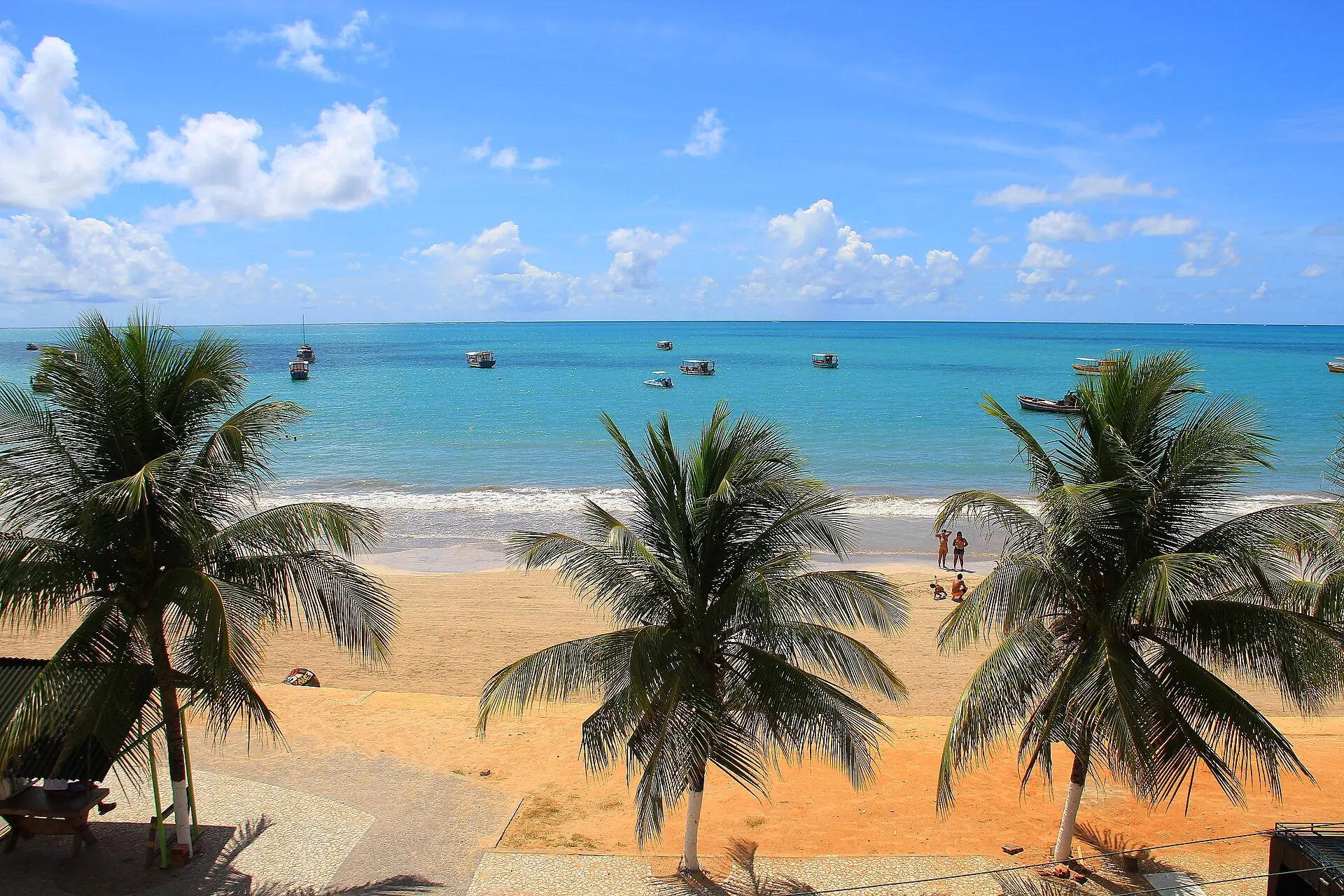 Praia de Maragogi, em Alagoas, com água turquesa, coqueiros na areia e jangadas ao largo